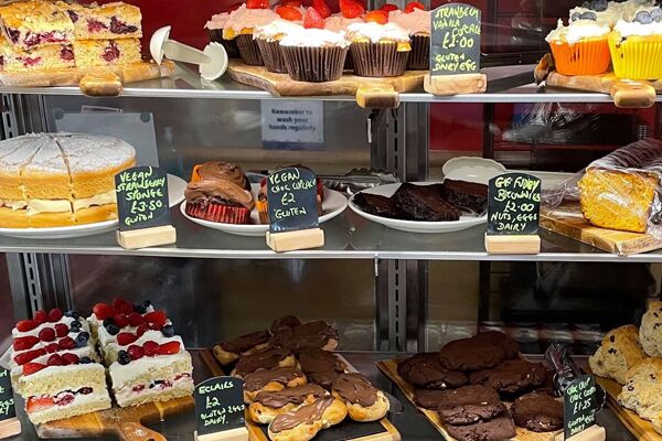 Three shelves of various cakes and vegan cakes